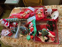 Overview of boxed Christmas decorations including stockings with plush figures, small trees, wreath, and plate.