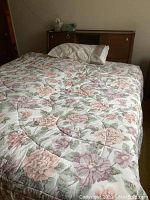 Bed frame with mid-century modern headboard shown with floral bedding and pillow in a carpeted room under natural light.