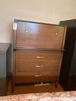 Front view of cabinet with closed drop-front and three drawers