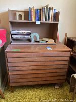 Front view of mid-century modern dresser with top open shelving loaded with books