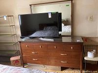 Wide view of walnut-finish dresser and matching mirror with TV on top