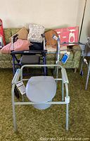 Photo of commode chair, rollator walker, and blankets on a green patterned sofa.