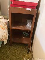 Front view of the brown metal side table with two shelves, showing some dust and wear.