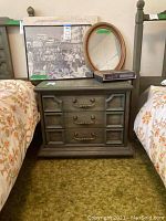 Photo of two matching Stanley nightstands placed between two twin beds, showing three-drawer design with brass handles and paneled sides, measuring 26x16x23 inches.