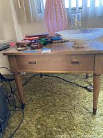 Front and top view of wooden occasional table showing square shape, single drawer, and various items on top (items not included).