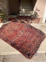 Three rugs laid out on concrete porch showing largest rug at front and two others in background