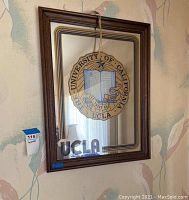 Full view of the UCLA hanging wall mirror showing the framed mirror with UCLA seal and 'UCLA' text.