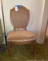 Front view of one vintage cane back dining chair showing cane backrest and upholstered seat.