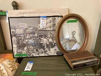 Photo showing vintage LA black and white framed picture, small oval mirror, and vintage clock radio on a table.