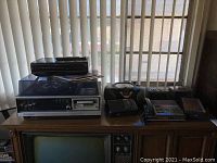 Image showing a wooden table with a vintage Panasonic record player with dust cover, two black clock radios, and a black stereo cassette player on top.