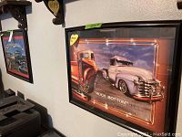 Photo of framed poster titled 'Rock Bottom' showing two vintage pickup trucks in warm tones.
