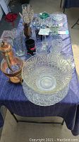 Overall table setup showing various crystal and glassware items arranged on a blue tablecloth.