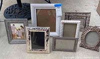 Multiple assorted picture frames displayed together on a surface; shows variety of styles and sizes.