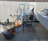 Shows an overview of the lot items including dollies, metal racks, baskets, and boxes placed outside near lattice fence