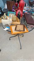 Photo of vases, frames, and assorted figurines on round metal table.
