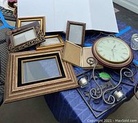 Full lot displayed on blue table showing clock, frames of various sizes, and metal hanging candle holders.