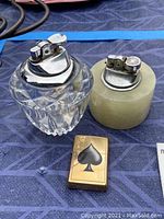 Photo of three vintage lighters: Zippo brass lighter with spade symbol, glass table lighter, and royal stone table lighter.
