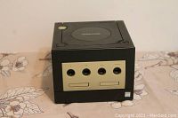 Front view of the black Nintendo GameCube showing controller and memory card ports on a floral surface.