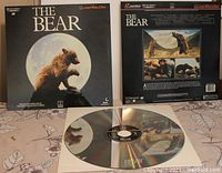 Front and back cover artwork laid out behind a Laserdisc with The Bear film label.