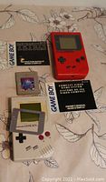 Photo showing white and red Nintendo Game Boys, Tetris cartridge, Tetris instruction booklet, owner's manual, and screen protector.