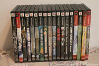 Photo shows front view of 17 PlayStation 2 game cases aligned side by side, titles clearly visible.