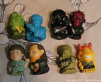 Photo showing 8 Star Wars character erasers including Darth Vader, Darth Maul, and Jar Jar Binks on floral fabric background.