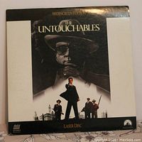 Front cover of The Untouchables LaserDisc showcasing the movie poster design featuring characters and title in black and white with some color accents at the bottom.