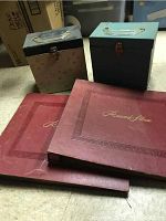 Two carry cases with vinyl records inside along with three red record album binders on floor.