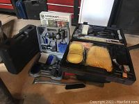 Photo showing Carecraft Automotive Maintenance Kit in grey case containing various brushes and detailing tools, with yellow and orange polishing pads in open black case nearby.