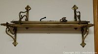 Photo of large brass wall rack with decorative end mounts