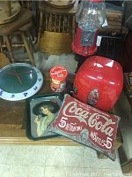 Overview of all Coca Cola items including bubble gum machine, mini fridge, clock, pillow, trays and tin can