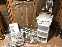 Complete view of multiple Elfa wire mesh drawers, wire baskets, mounting rails, packaged items, and a clear plastic four-drawer storage organizer.