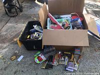 Overview photo showing a box full of painting supplies including paint brushes, rollers, sanding tools, tapes and cleaning materials.