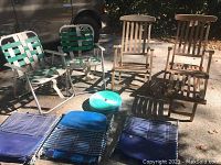 Full view of six outdoor chairs on concrete with shadows, two wooden Steamer chairs and four webbed chairs with replacement webbing visible