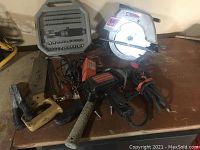 Various power and hand tools including craftsman circular saw, drills, hammer, screwdrivers, sockets set, grinder, and saw blades seen arranged on table showing the variety and condition without packaging.