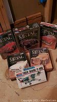 Photo showing five Monogram die-cast metal car model kits in original boxes, positioned on a concrete floor.