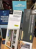 Three boxed wardrobe organizers and storage closet stacked together showing product details and brand.