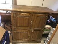 Full view of the wooden ice box cabinet with four doors and brass hardware