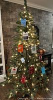 Full view of 6-foot pre-lit artificial Christmas tree with assorted gift card ornaments hung on branches