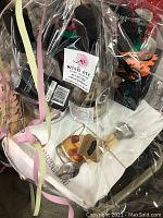 Full view of cocktail night gift set wrapped in clear cellophane showing barware and mixers inside along with ribbons and tags.