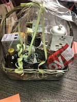 Gift basket wrapped in clear plastic, showing coffee-related items inside including cans, mugs, biscotti, and a gift card.