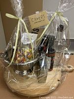 Cellophane-wrapped kitchen items on round wooden serving board