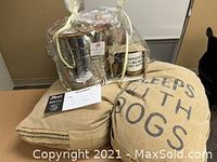 Photo of gift basket wrapped in clear cellophane showing pillow, treat canister, mug, and gift certificate inside.