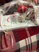 Items arranged on red plaid cushion: serving tray, mugs, ornament, card