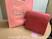 Red faux leather Matt & Nat bag displayed next to pink Starlet shopping bag and pink gift card