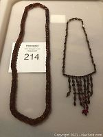 Photo showing two red bead necklaces laid flat side by side with a MaxSold auction card visible.
