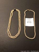 Both necklaces laid flat on dark background