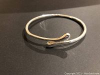 Front angle of the silver-tone adjustable cuff bracelet on a black background highlighting the shiny finish and open-ended design