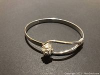 Bracelet bangle viewed from top angle showing the thin band and flower embellishment within the teardrop-shaped loop.