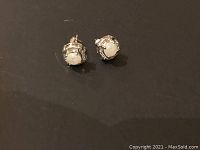 Close-up photo of earrings showing central light-colored stones with accent stones on metal mountings.